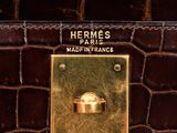 the handle of a brown purse with a gold plate on it