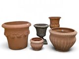 quatre pots en terre cuite posés les uns à côté des autres sur une surface blanche