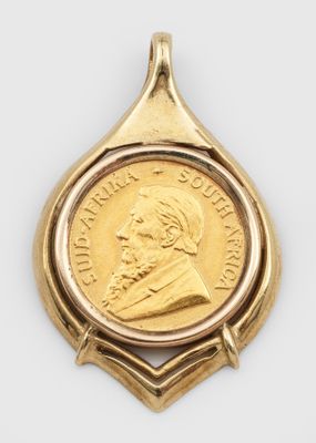 un gros plan d'une pièce de monnaie sertie dans un pendentif en or, sur fond blanc