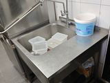un évier en inox dans une cuisine avec une poubelle posée sur le plan de travail