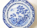 a blue and white plate with a bird and flowers on it