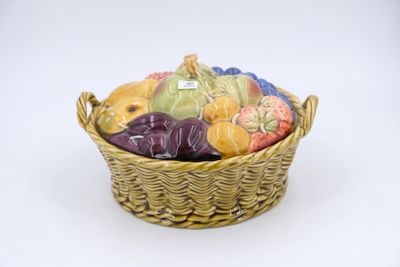 un panier en osier rempli de fruits variés posé sur une surface blanche