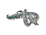 a close up of a brooch with diamonds and emeralds