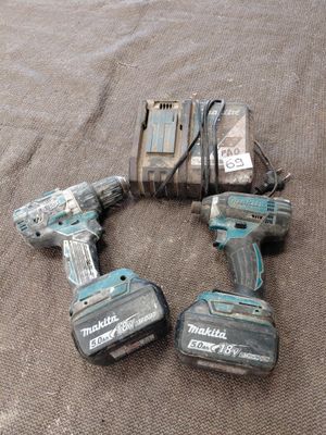 deux perceuses-visseuses sans fil Makitera et deux batteries posées sur une surface marron