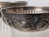 two silver bowls sitting on a clear shelf
