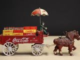 a toy horse pulling a cart with coca cola on it