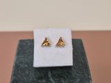 a pair of gold earrings sitting on top of a marble block