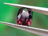 un gros plan d'un diamant rouge tenu par une pince