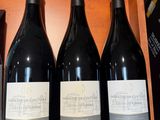trois bouteilles de vin sont posées sur une étagère dans un magasin de vins