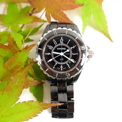a black watch sitting on top of a black bracelet