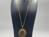 a necklace with a gold medallion on a black mannequin