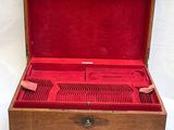 an open wooden box with red velvet lining and silverware in it