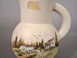 a white pitcher with a picture of a farm scene on it