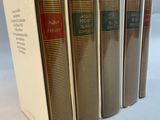 four books are lined up in a row on a white surface