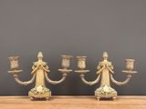 pair of antique brass candelabs on wooden table against grey wall