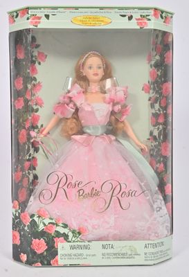 La poupée se trouve dans une boîte, vêtue d'une robe rose et d'un ruban à nouer.