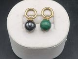 pair of green and black stone earrings in a white box