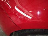 the front bumper of a red car with scratches on it