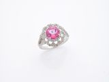 une photo d'une bague sertie d'un diamant rose et blanc, posée sur une surface blanche