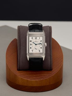 a watch that is on a wooden stand on a table