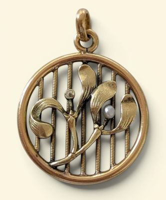 a close up of a pendant with a flower and a bird on it