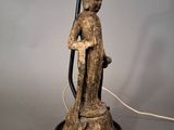 a statue of a person holding a lamp on a table