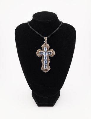 a silver cross pendant on a black mannequin necklace