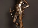 a bronze statue of a woman holding a sword on top of a wooden table