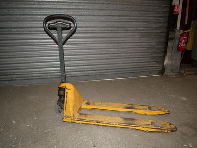 un chariot élévateur jaune garé devant une porte de garage