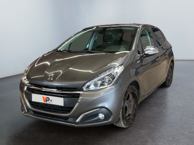 La voiture argentée est garée dans une grande pièce au sol noir.