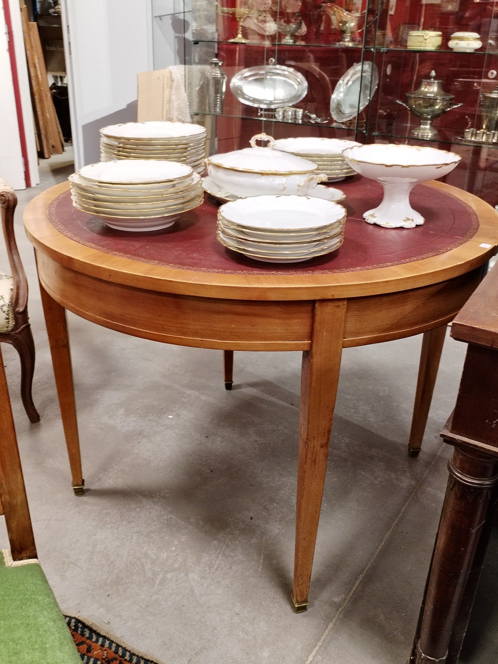 Table ronde en merisier ; plateau recouvert d'un cuir.