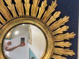 a gold sunburst mirror hanging on the wall