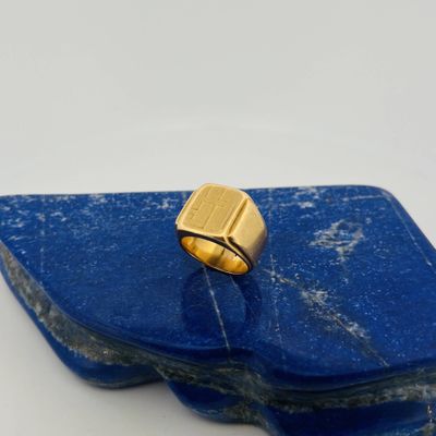 une image représentant une bague en or posée sur une pierre bleue