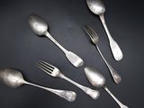 five silver spoons and a fork on a black surface