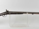 un vieux pistolet au canon en bois, exposé sur un support blanc