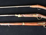 three old guns are lined up on a black surface