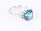 a close up of a ring with a blue topaz stone and diamonds