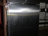 a black refrigerator in a kitchen with a red refrigerator in the background