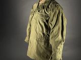 an olive green jacket on a mannequin stand against a gray background