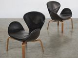 two black leather chairs with wooden legs in a white room