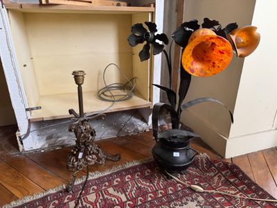 un vase avec des fleurs et une lampe posée par terre