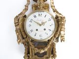 a gold clock hanging on the wall on a white wall