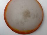 an orange and white frisbee sitting on a white surface