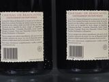 two bottles of wine sitting on top of a table next to each other
