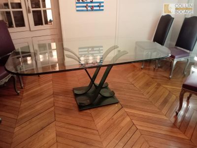 une table en verre avec un piètement en métal au milieu d'une pièce