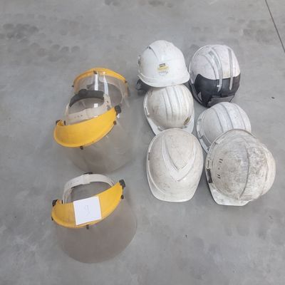 several hard hats are lined up on a cement floor
