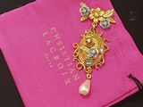 pink bag with a gold and pearl brooch on it
