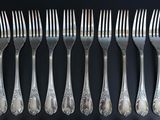 six forks and six spoons on a black table