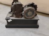 a bronze statue of a man sitting on a clock