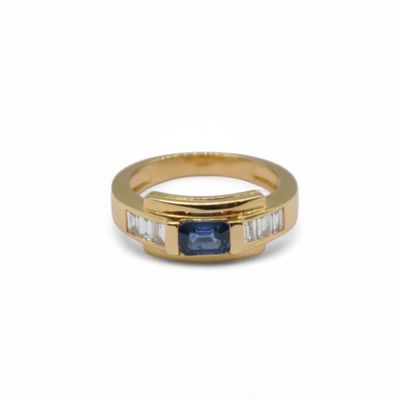 a close up of a gold ring with a blue sapphire and baguets